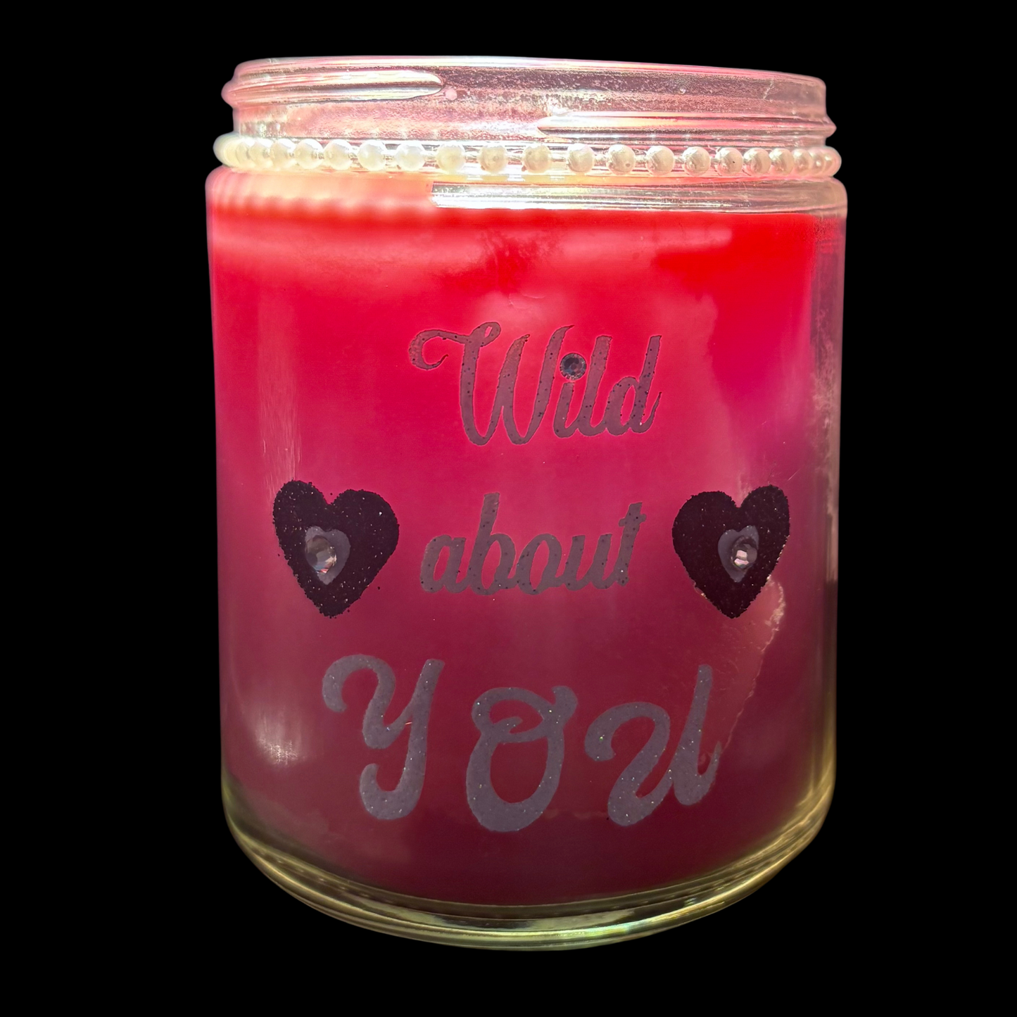 Pink candle in a glass jar with 'Wild about You' text and heart designs on a black background