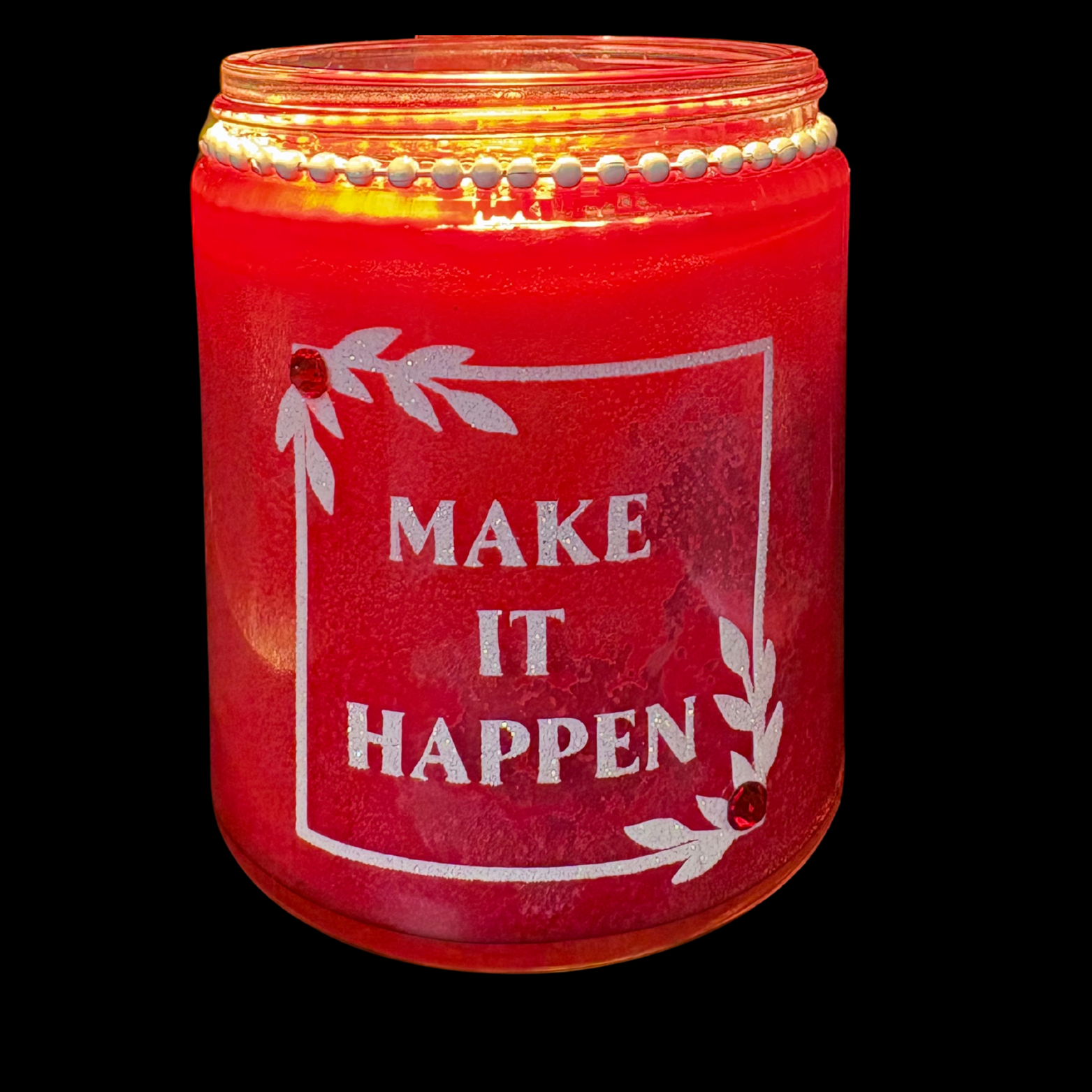 Red candle jar with 'Make It Happen' text on a black background