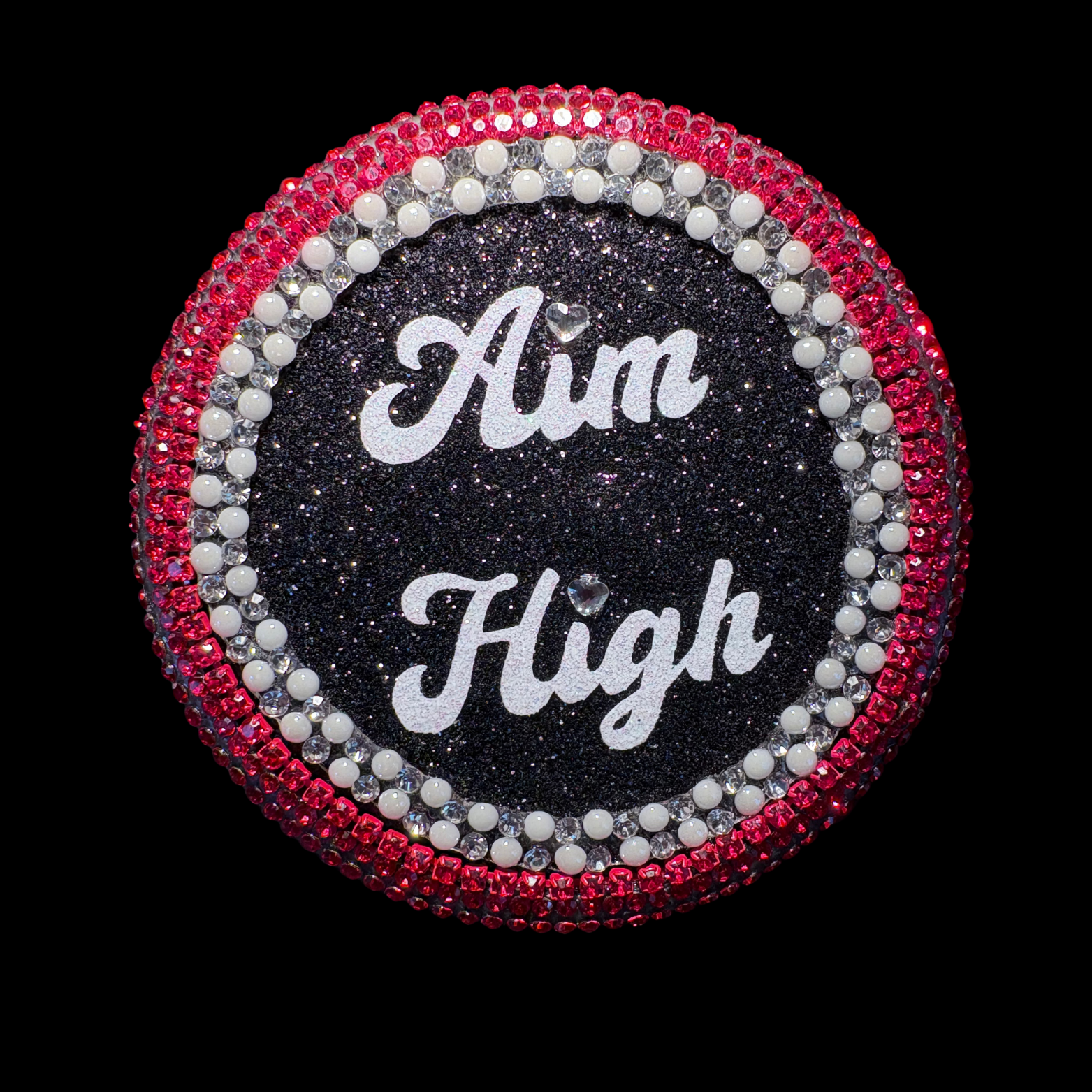 Circular decorative item with 'Aim High' text surrounded by red and silver embellishments on a black background.