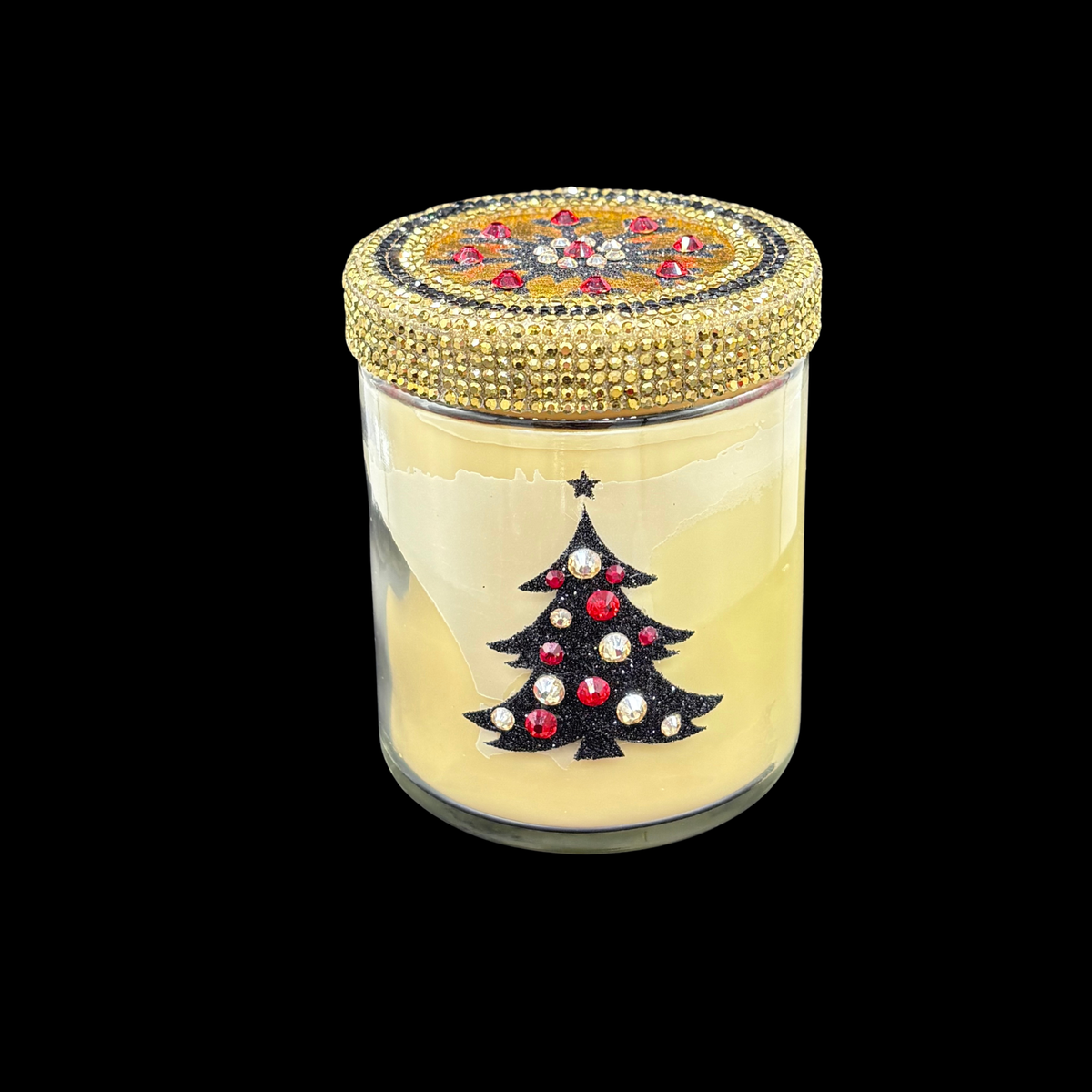 A holiday-themed scented candle in a clear glass jar with pale yellow wax, featuring a black Christmas tree decorated with red and white rhinestones on the front. The lid is heavily embellished with gold rhinestones and features a colorful circular pattern at the top.