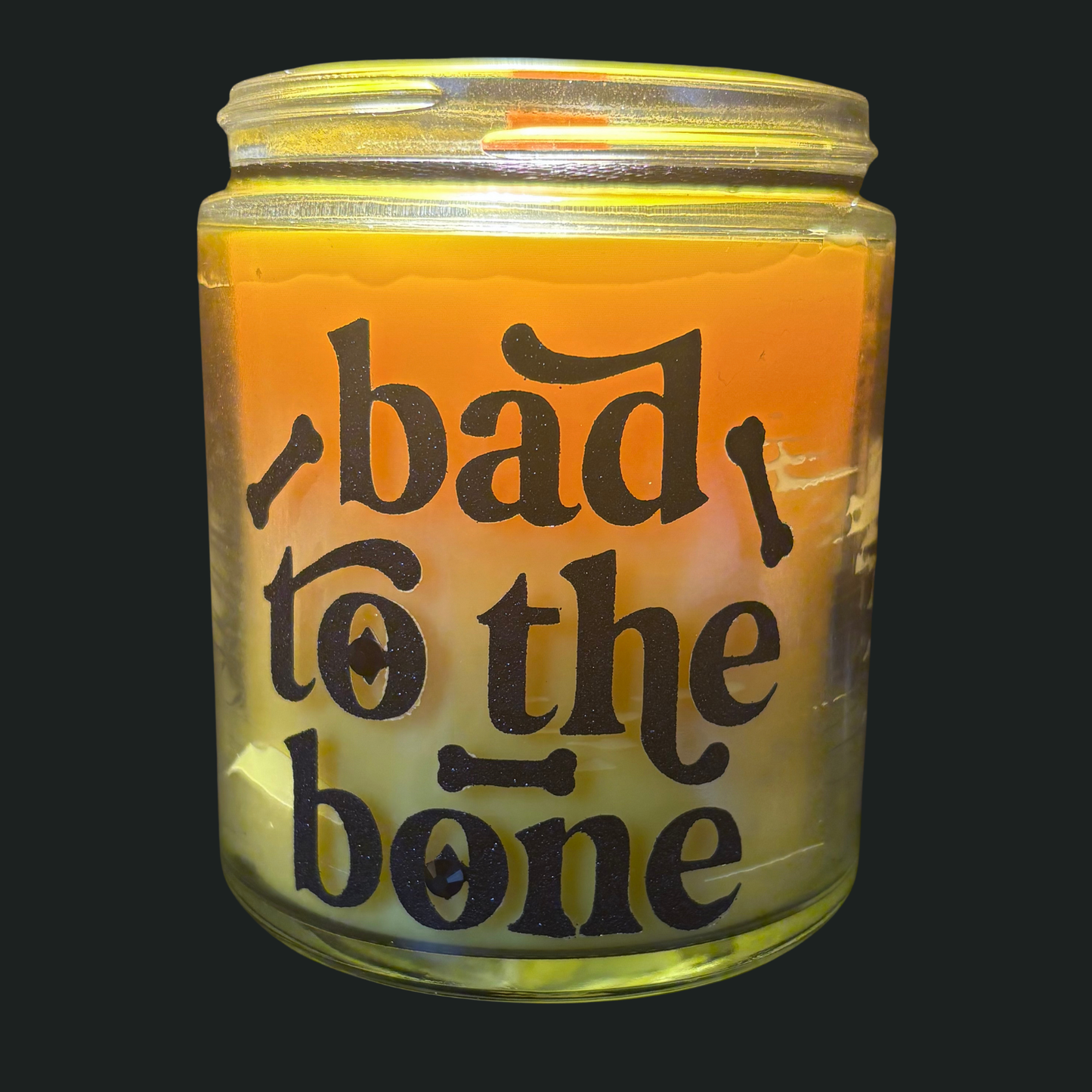 Candle in a glass jar with 'bad to the bone' text on a black background
