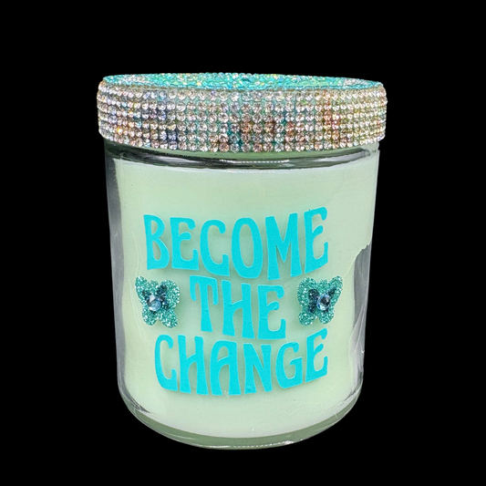 Candle jar with 'Become the Change' text and decorative lid on a black background