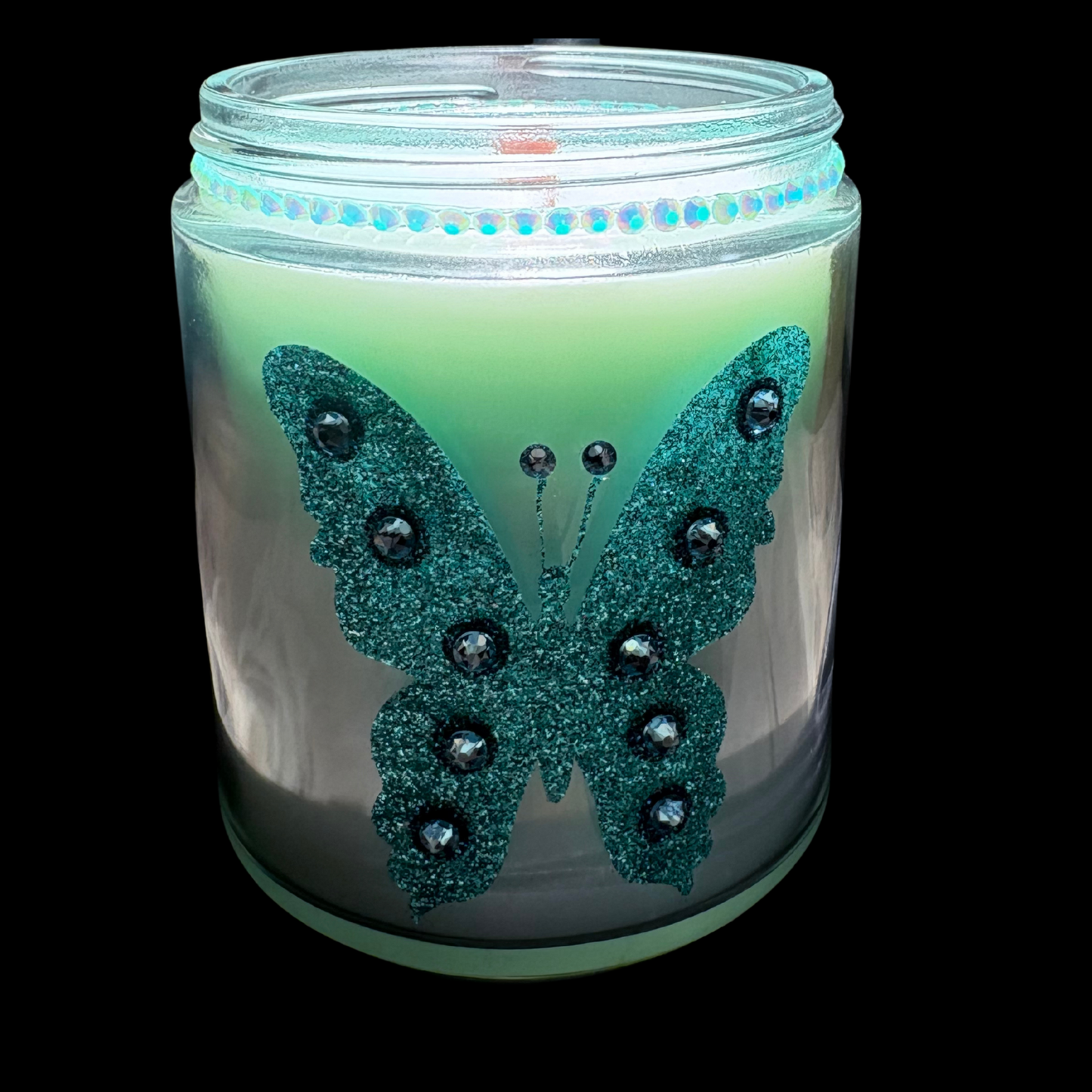 Candle in a jar with a decorative butterfly design on a black background
