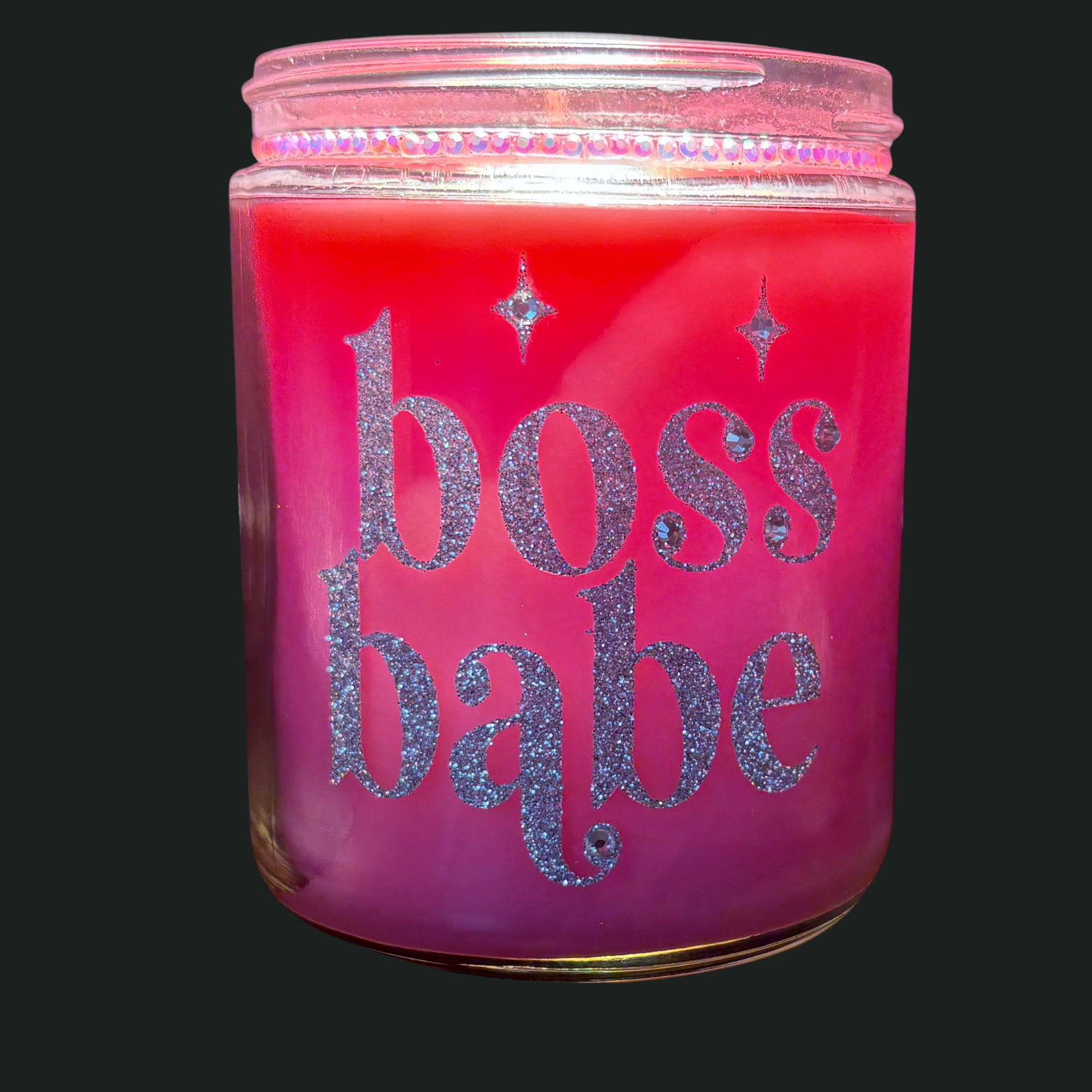 Pink candle jar with 'boss babe' text in glitter on a black background