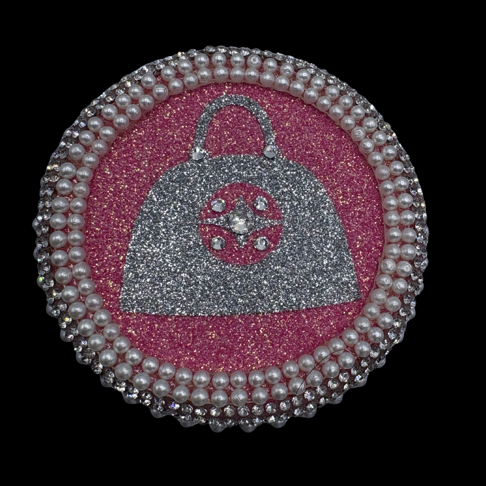 Decorative patch with a silver handbag design on a pink background, framed by pearls.
