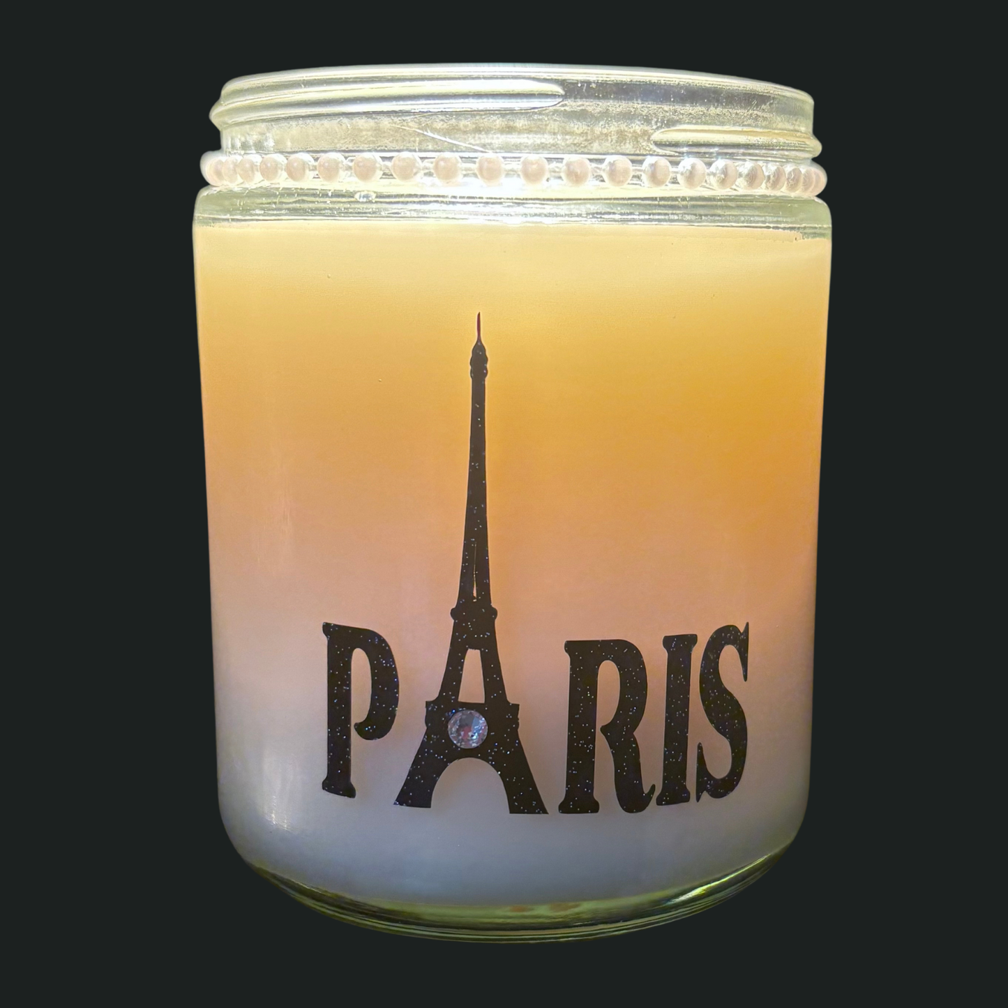 Candle in a glass jar with Eiffel Tower and 'Paris' text on a black background
