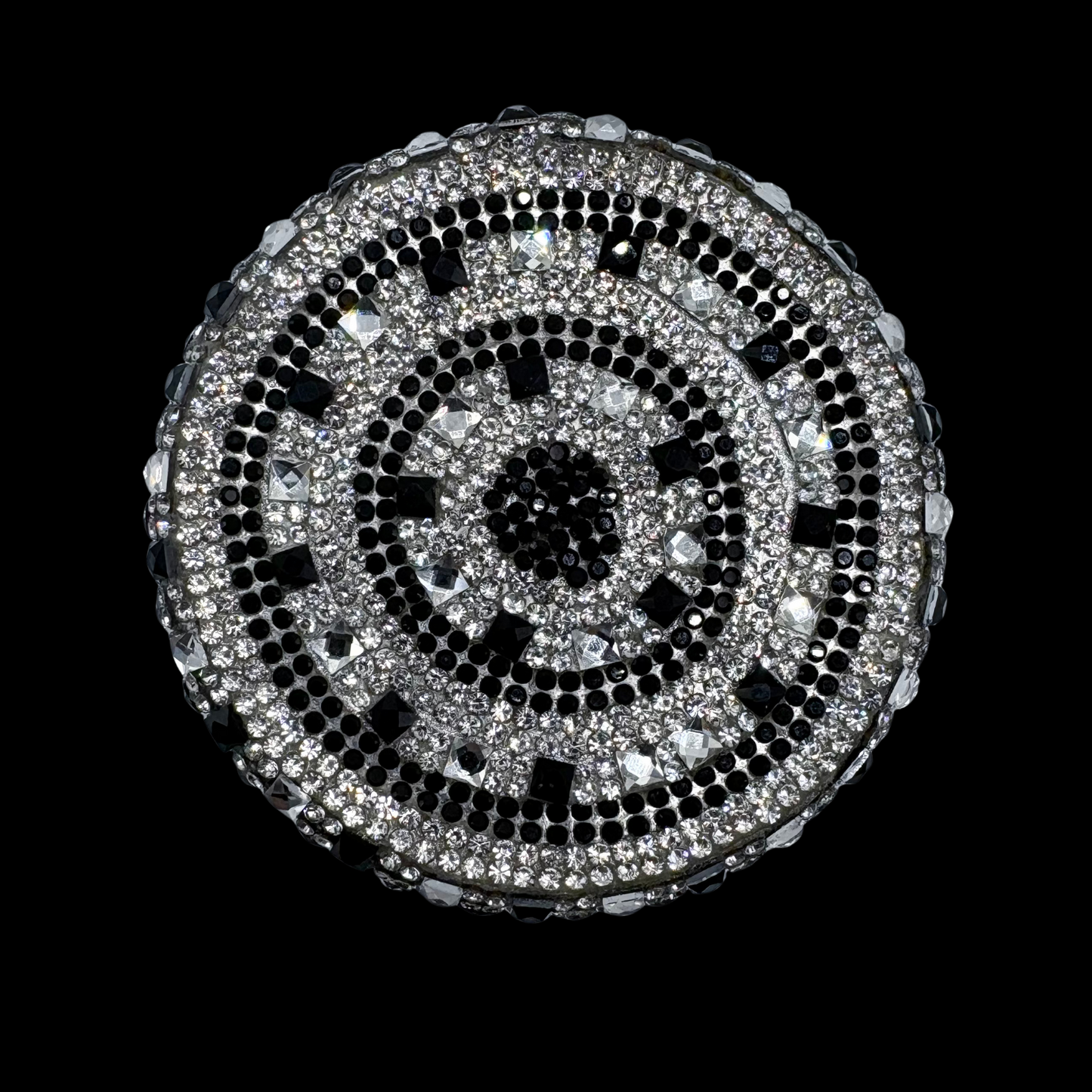 Round decorative item with black and silver pattern on a black background