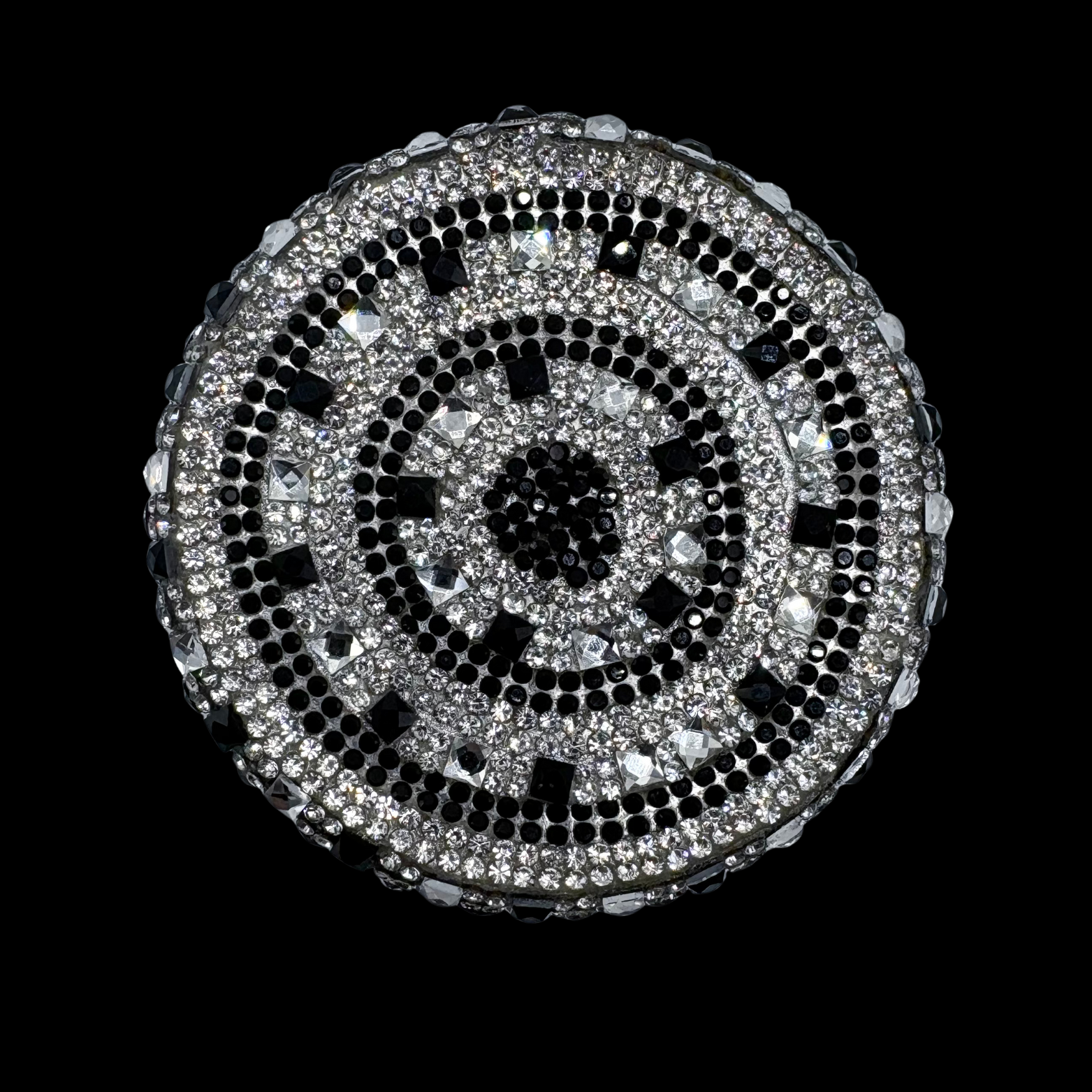Round decorative item with black and silver pattern on a black background