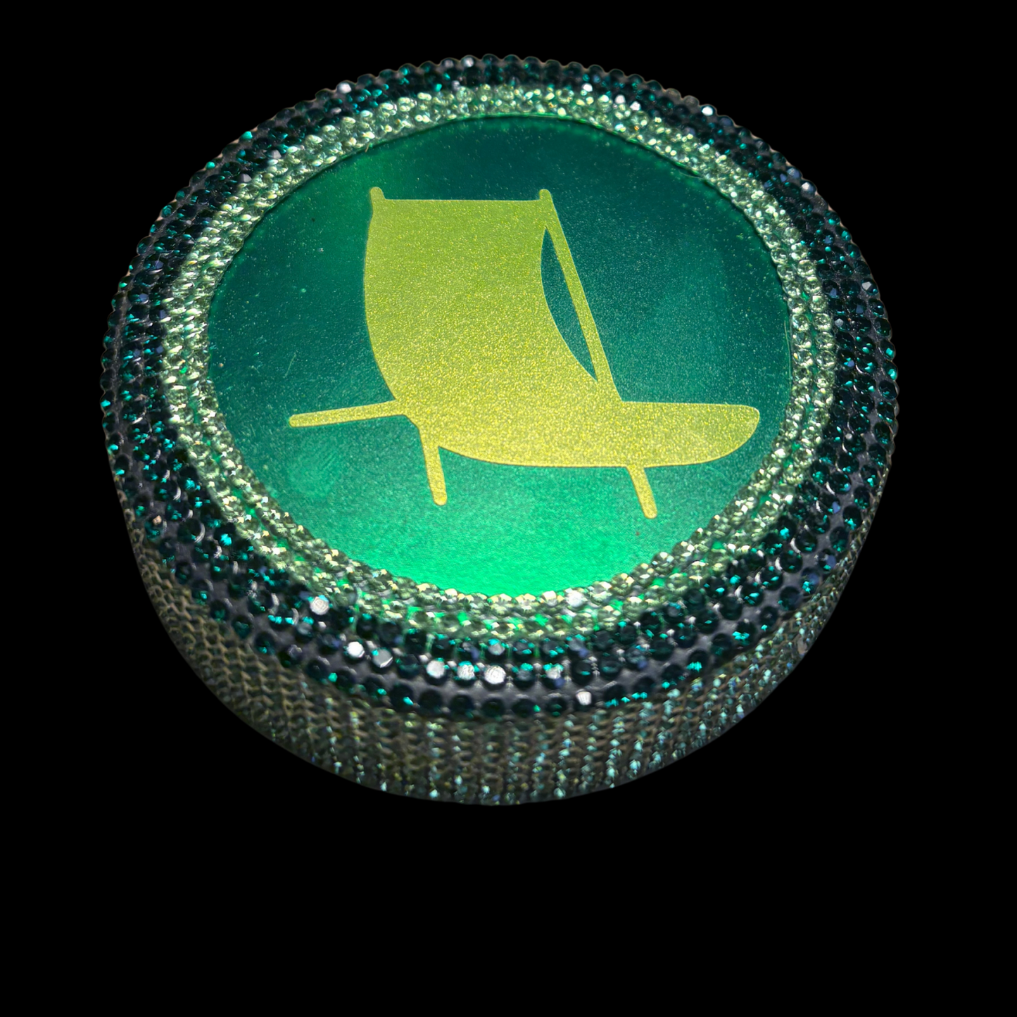Round green button with yellow sailboat icon on a black background
