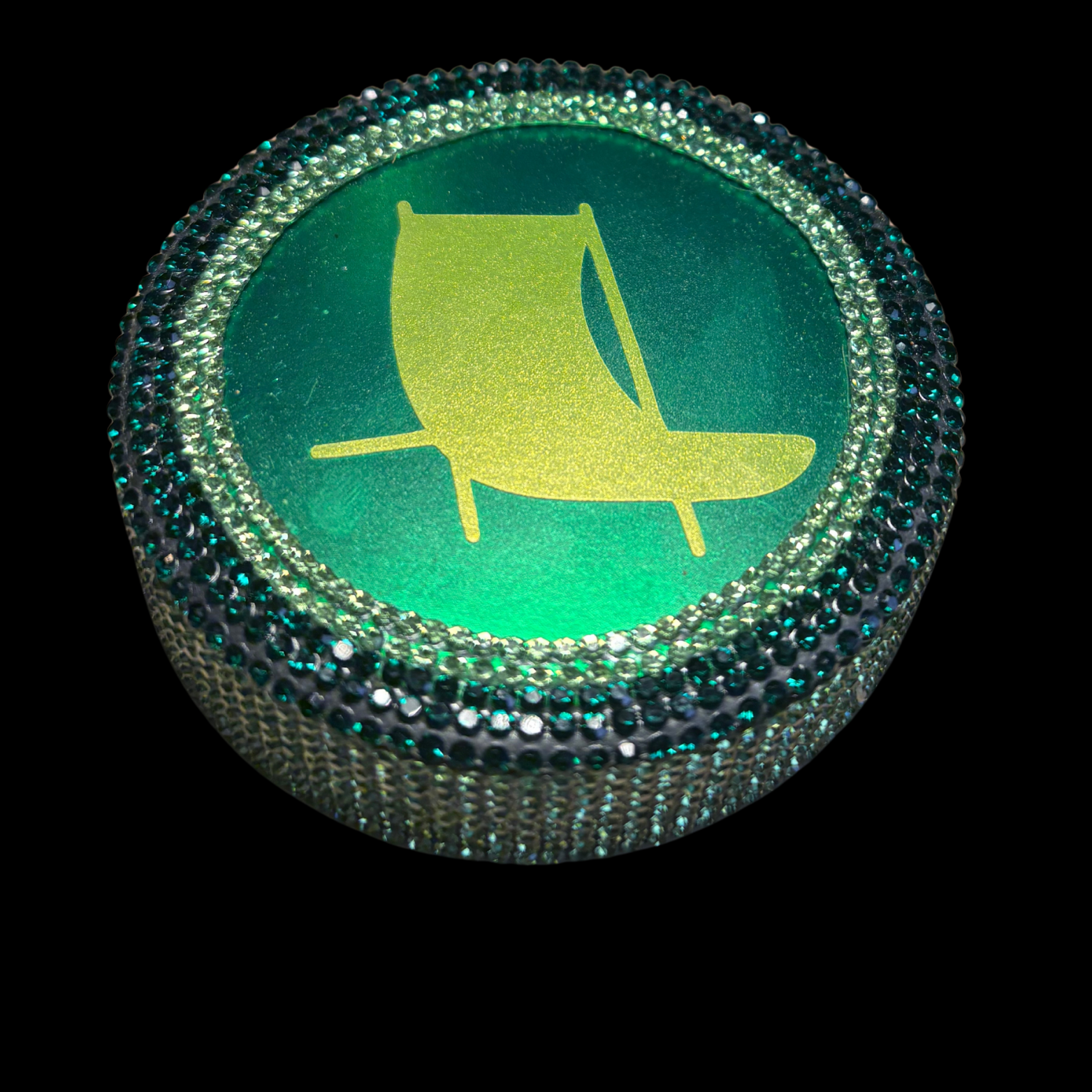 Round green button with yellow sailboat icon on a black background