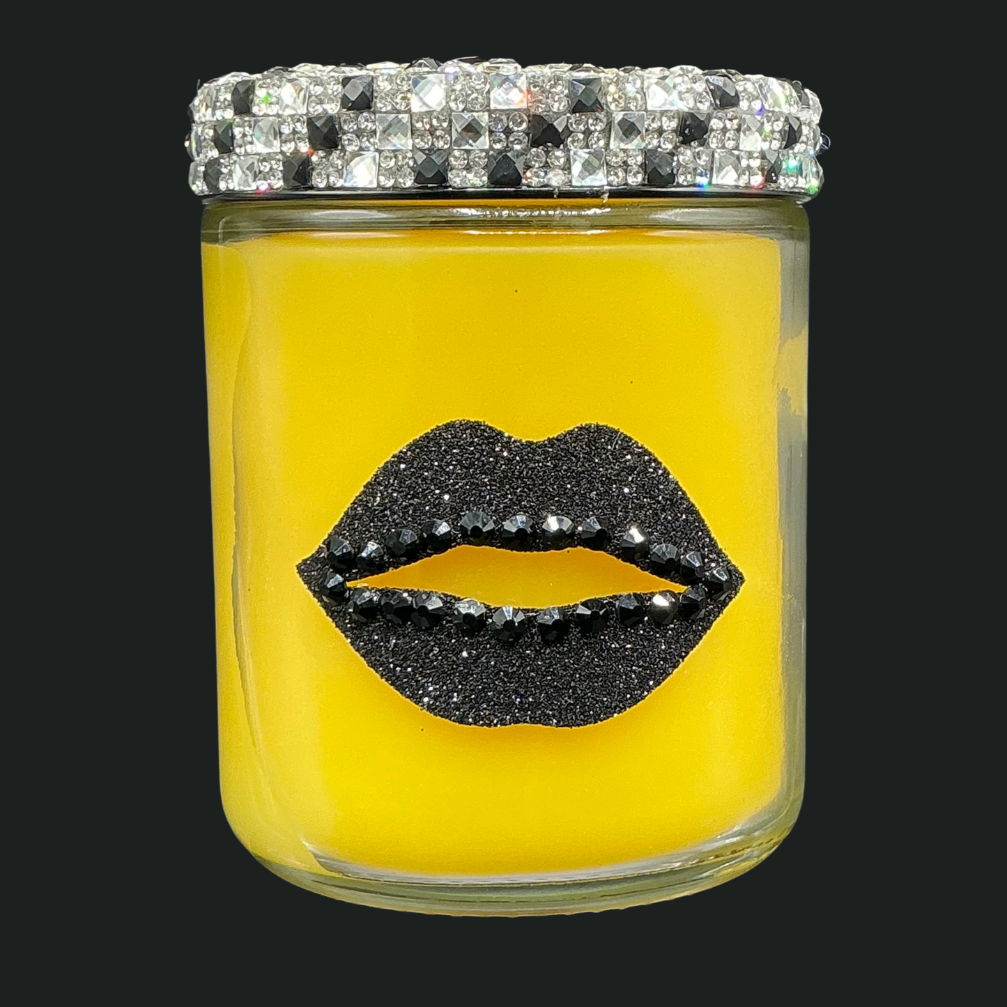 Yellow candle in a glass jar with black lip design and crystal lid on a black background