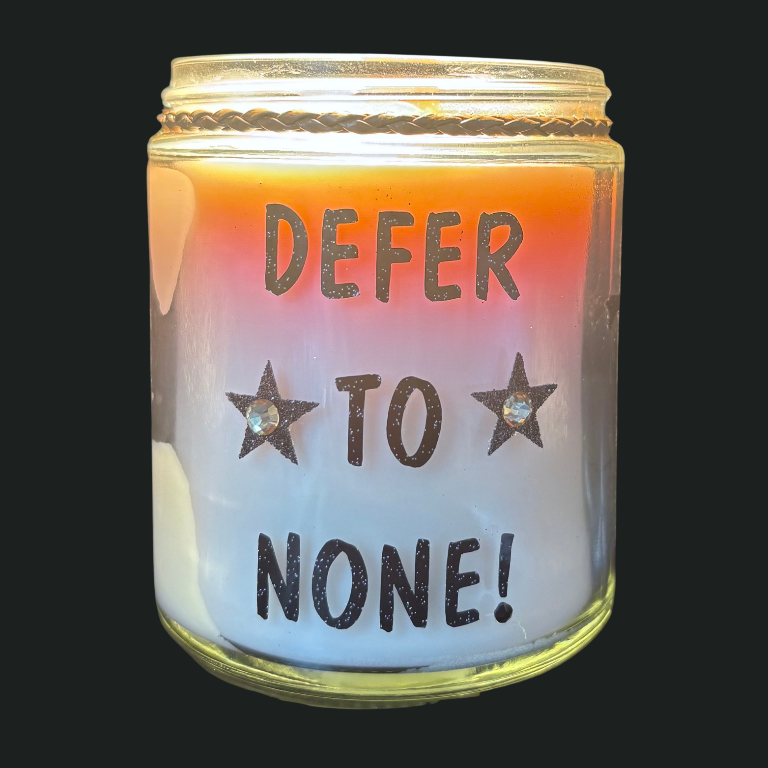 Glass jar with 'Defer to None!' text and star symbols, illuminated from within.