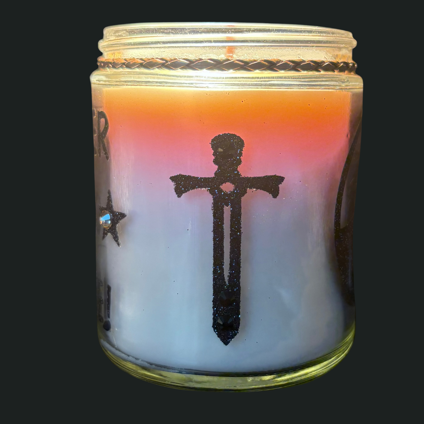 Candle in a glass jar with a black silhouette design on a dark background