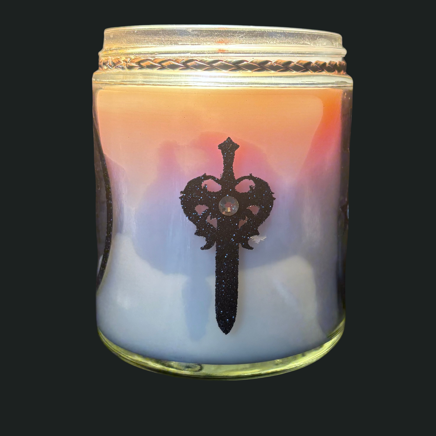 Candle in a glass jar with a decorative emblem on a black background