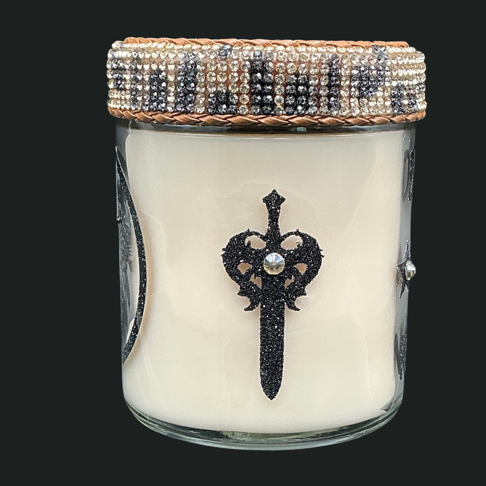 Candle in a glass jar with decorative lid featuring a sword and heart design.