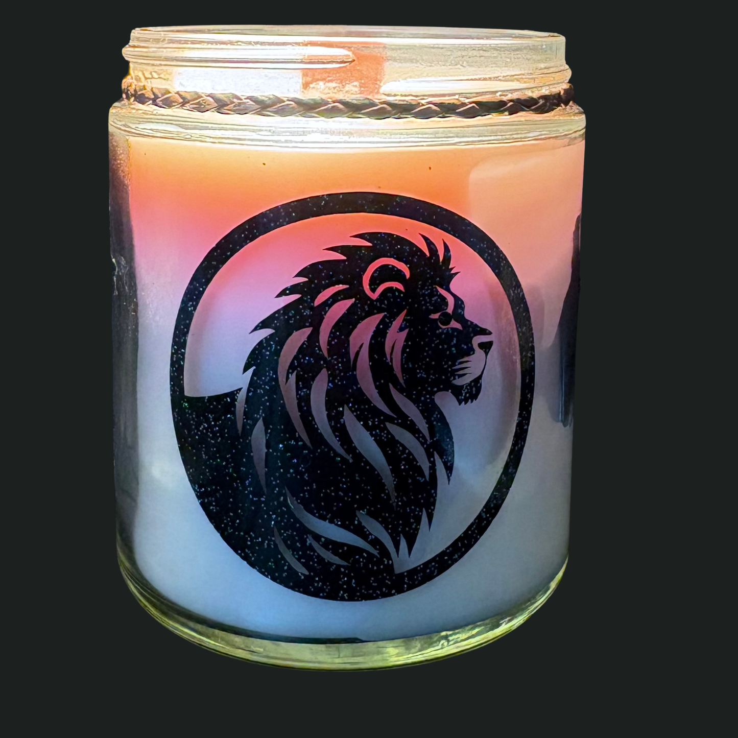 Candle in a glass jar with a lion design on a dark background
