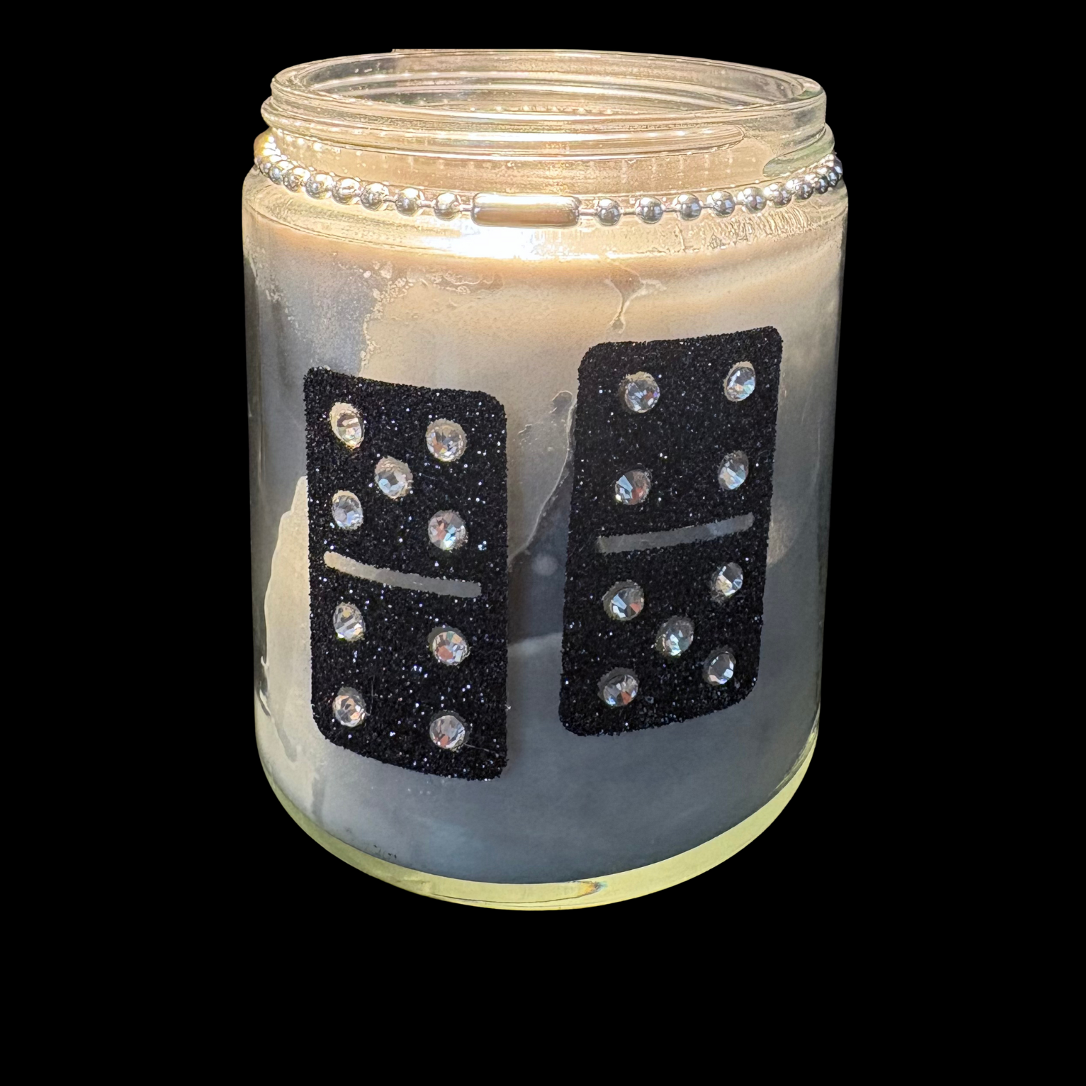 Candle in a jar with domino decorations on a white background