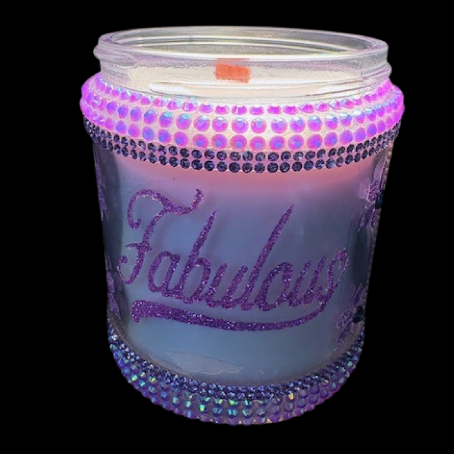 Candle in a jar with 'Fabulous' text and decorative stones on a black background