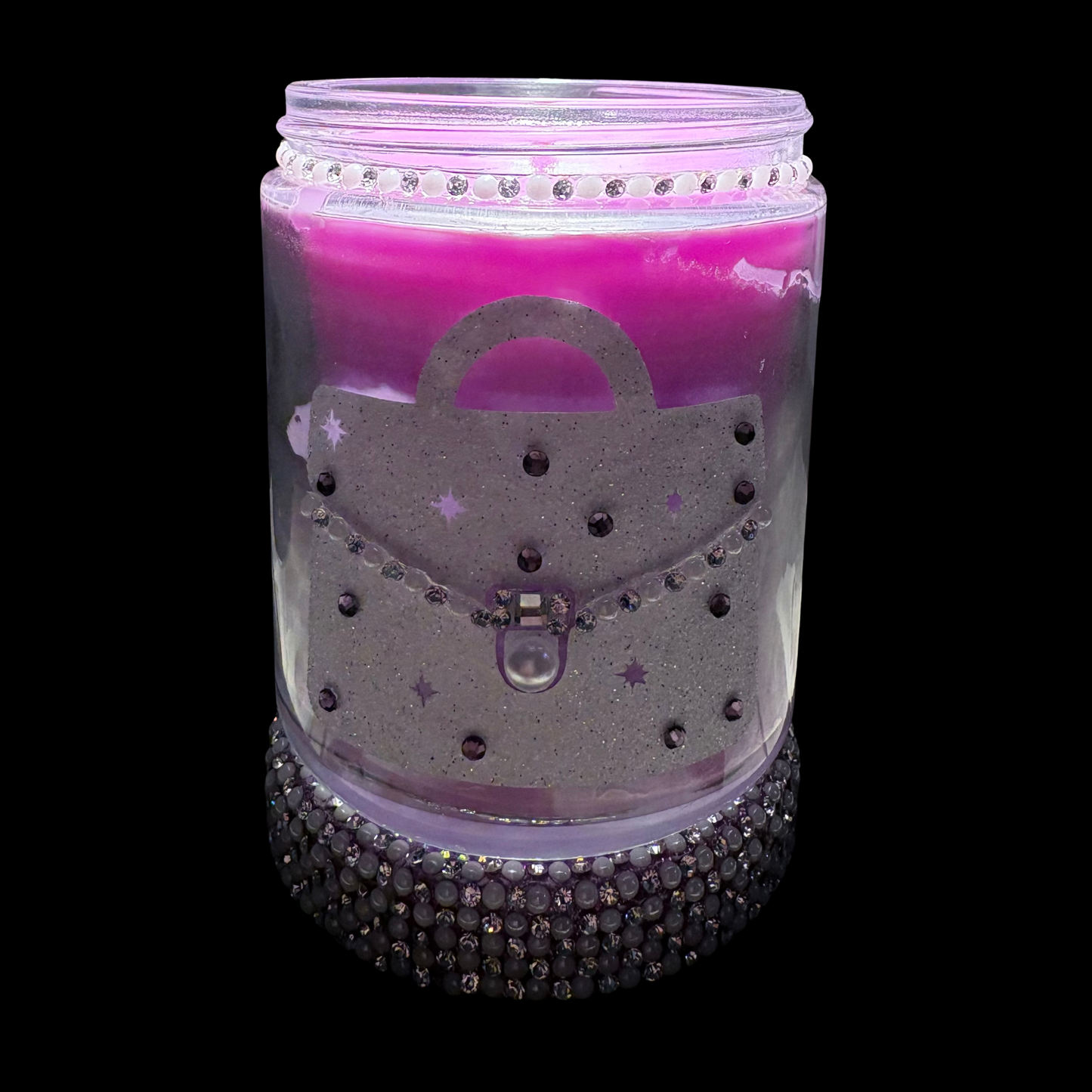 Decorative candle in a glass jar with pink wax, silver lid, and decorative elements on a black background