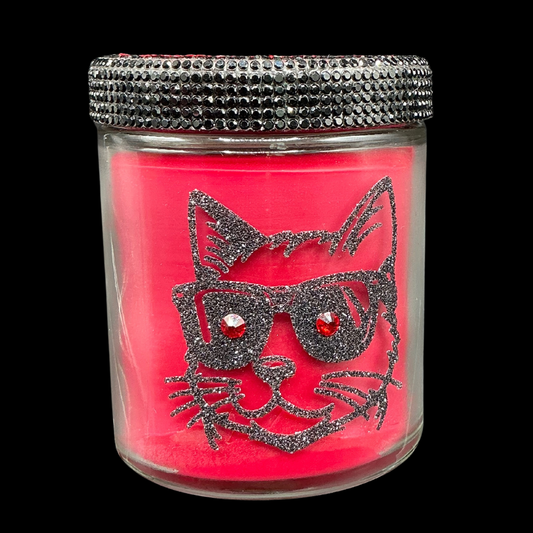 Pink candle in a glass jar with a cat design and silver lid on a black background