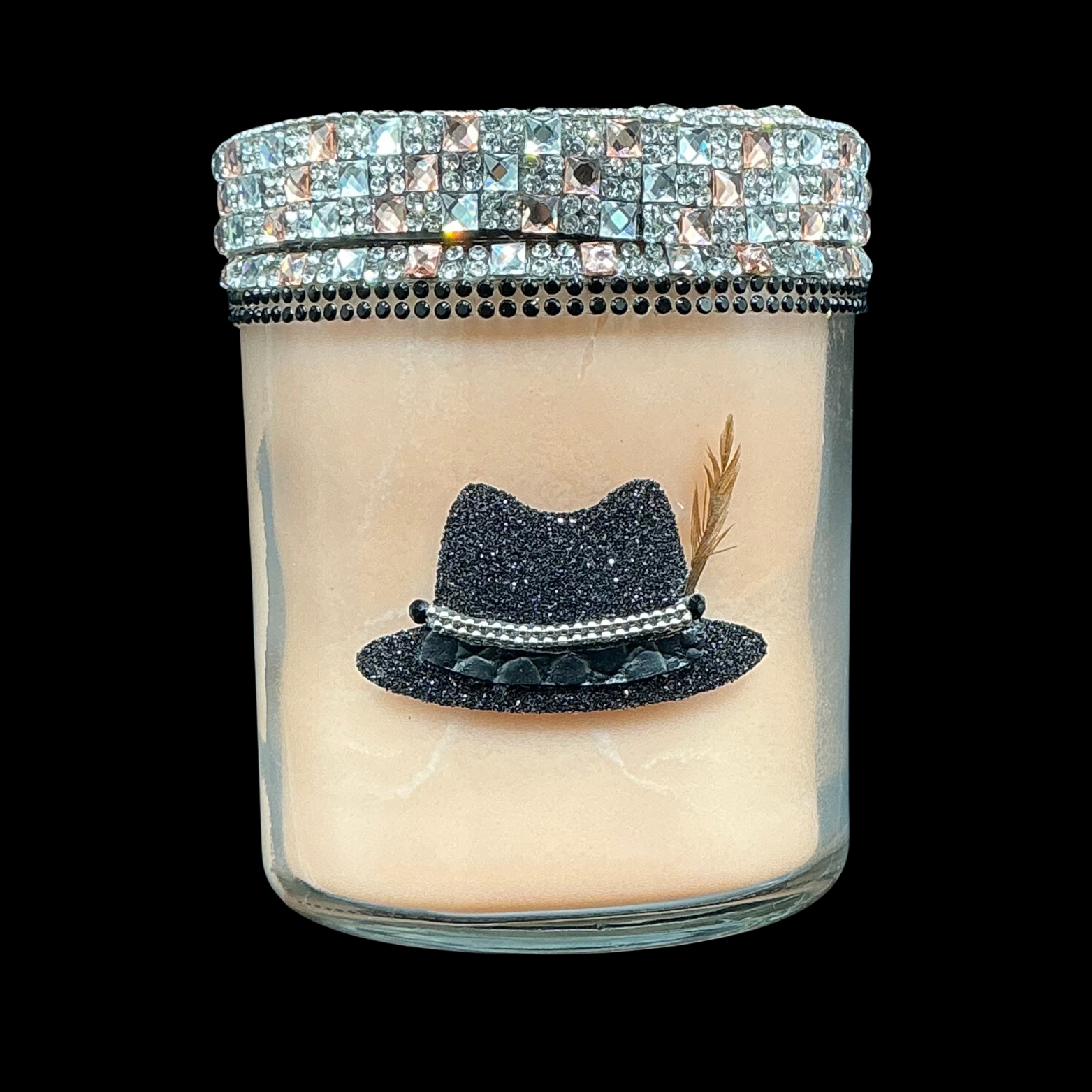 Candle with a decorative hat design and jeweled lid on a black background