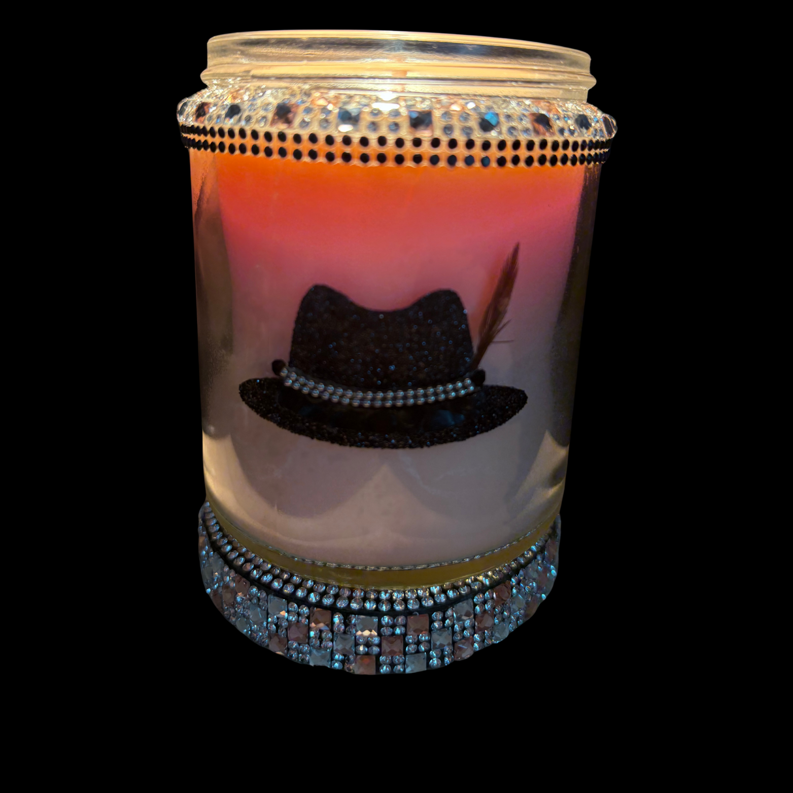 Candle in a jar with decorative top hat design and rhinestone embellishments on a black background