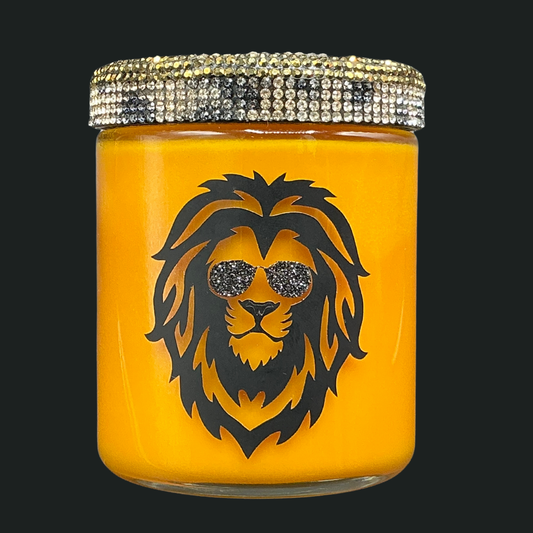 Yellow candle jar with a lion design and rhinestone lid on a black background