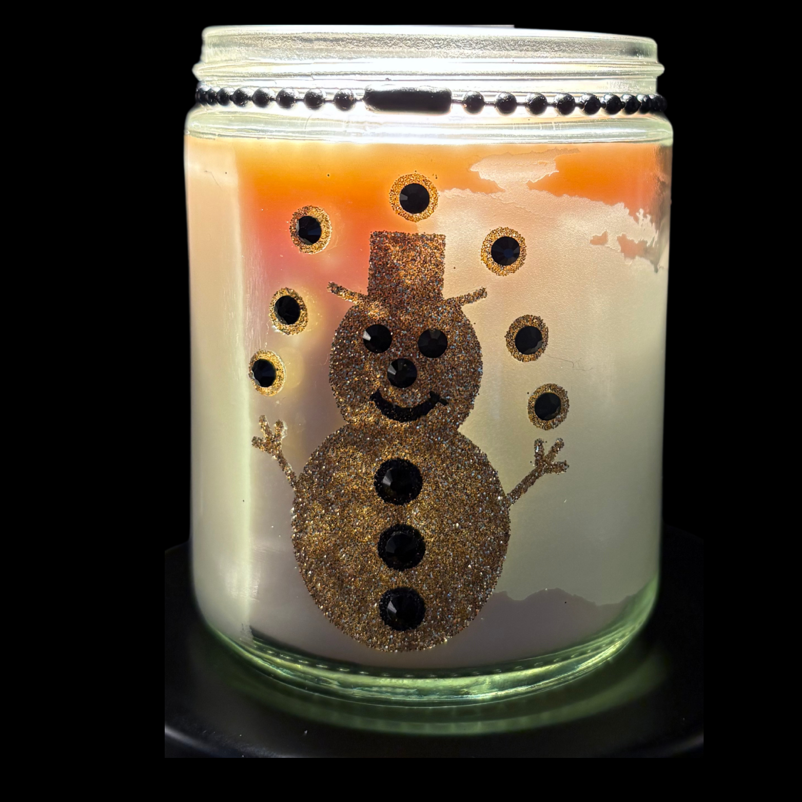 Candle in a jar with a snowman design on a black background