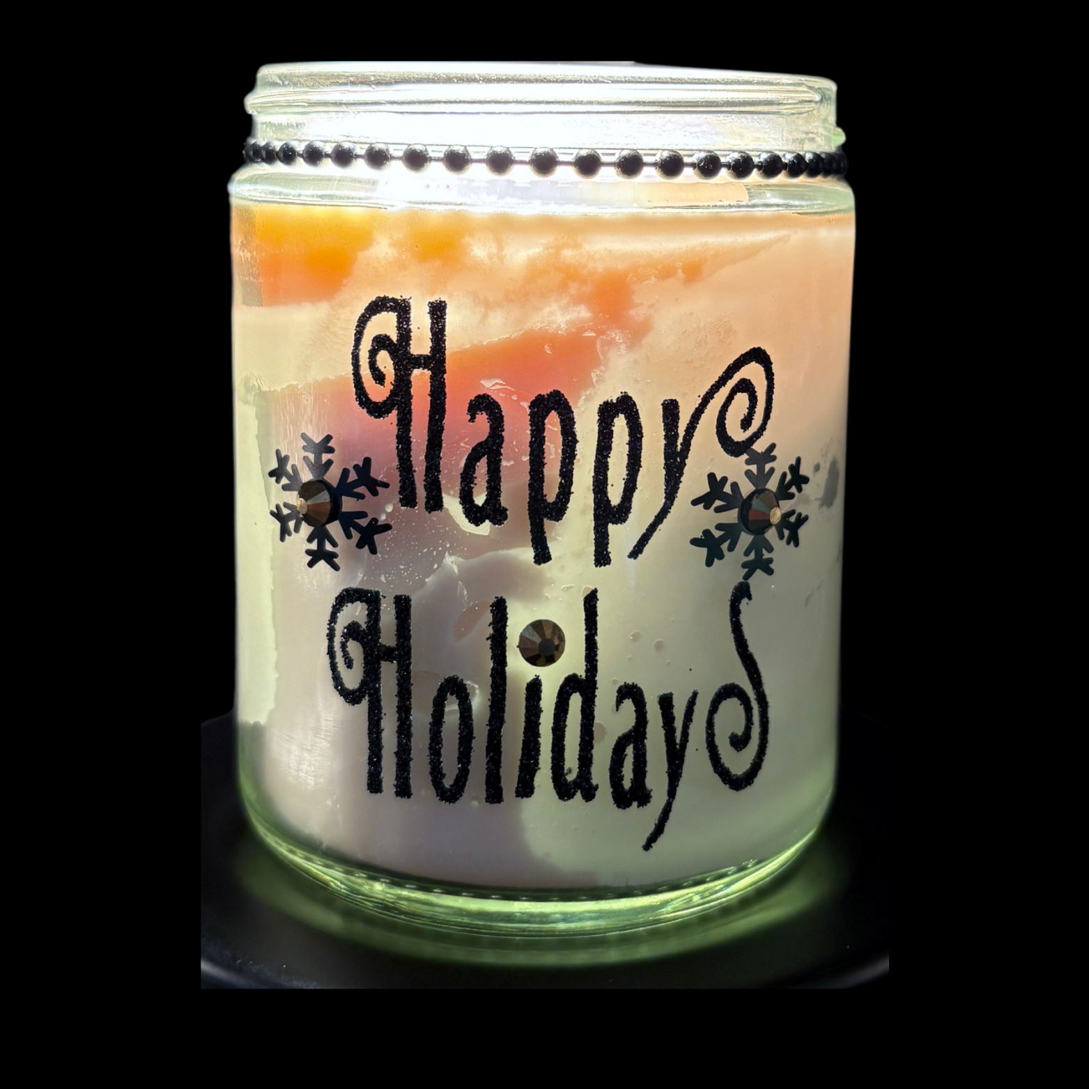 Candle in a glass jar with 'Happy Holidays' text on a black background