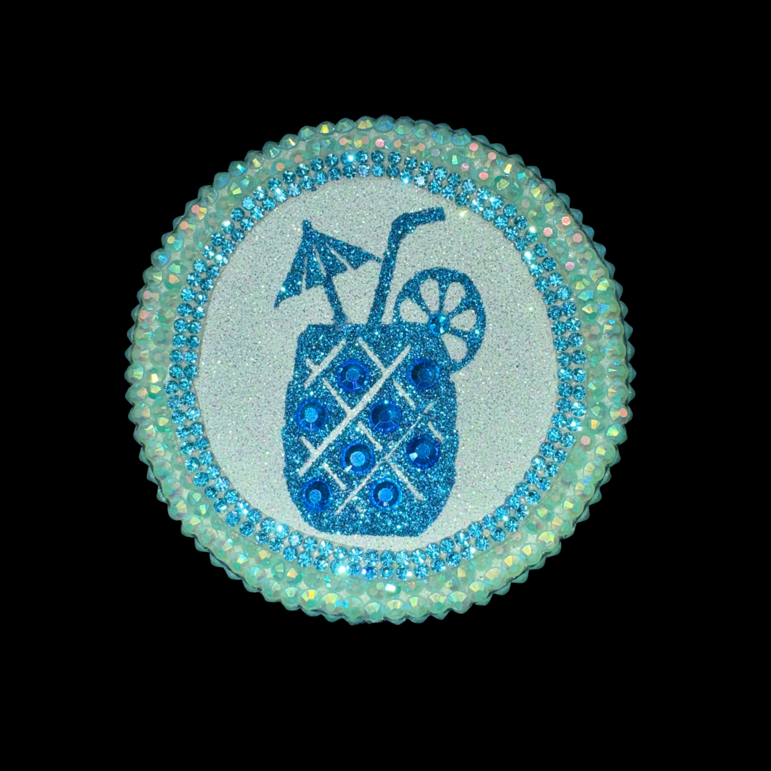 Decorative button with a blue drink icon and rhinestone border on a black background