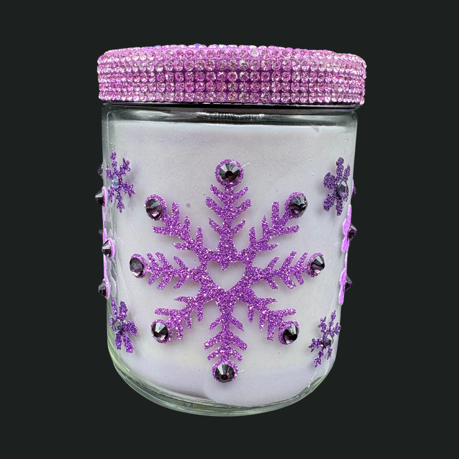 Glass jar with pink lid and purple snowflake decorations on a black background
