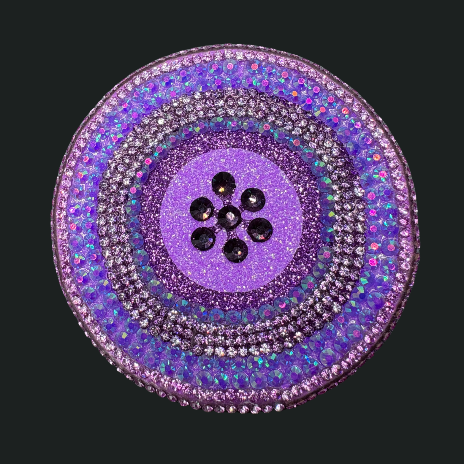 Decorative button with purple center and multicolored outer layers on a black background