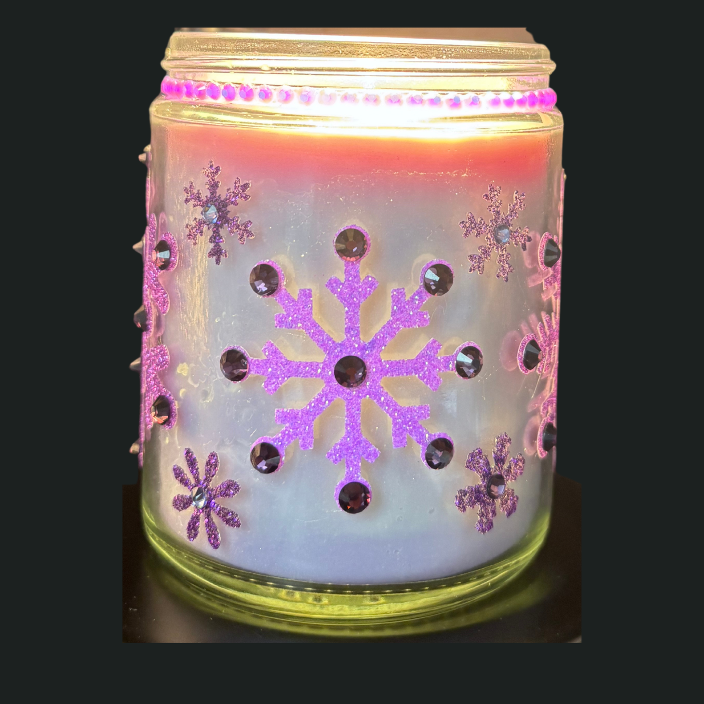 Decorative candle holder with snowflake designs and pink accents on a black background