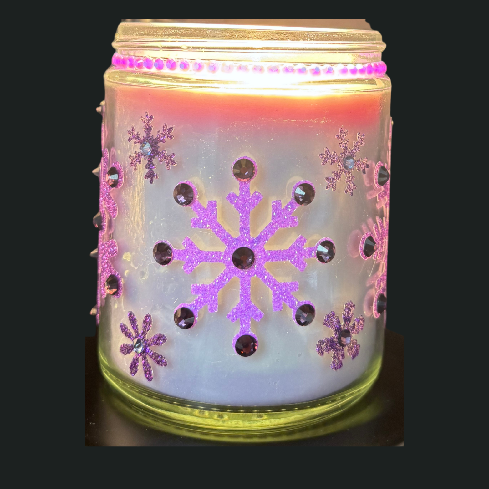 Decorative candle holder with snowflake designs and pink accents on a black background