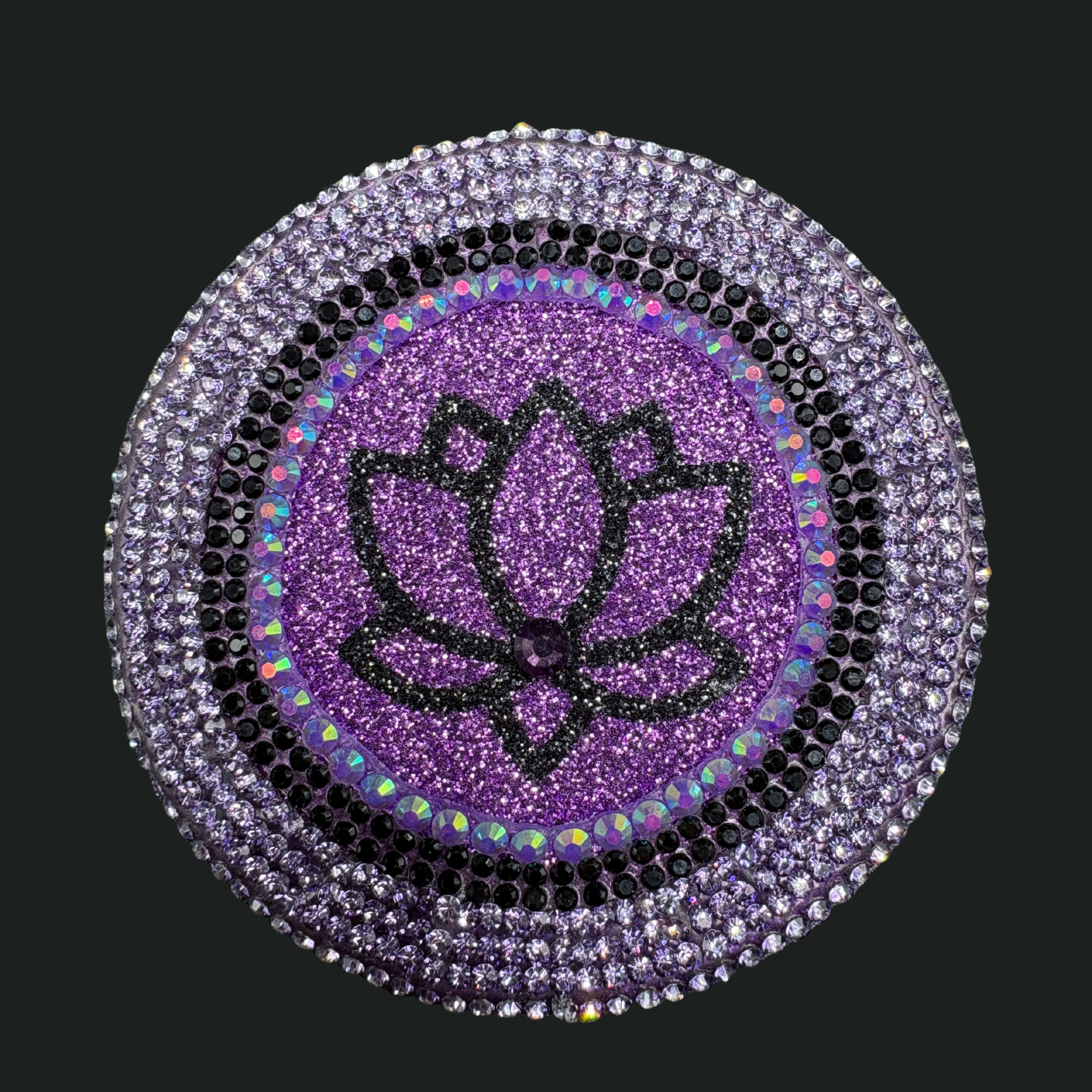 Decorative brooch with purple lotus flower and rhinestone border on a black background