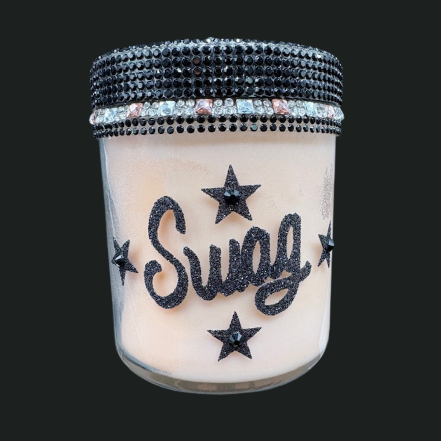 Candle in a glass jar with 'Sway' and star designs, topped with a rhinestone lid on a black background.
