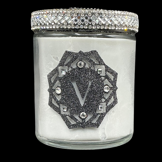 Glass jar with decorative lid featuring a logo and crystals on a black background