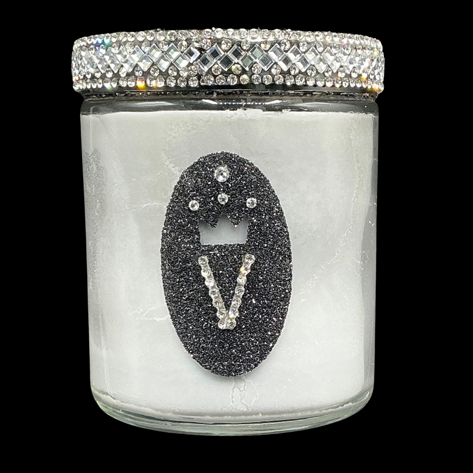 Decorative candle with a black 'V' design and crystal embellishments on a clear jar.
