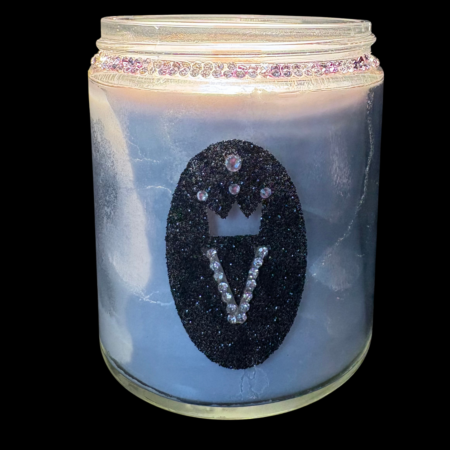 Candle in a glass jar with decorative design on a black background