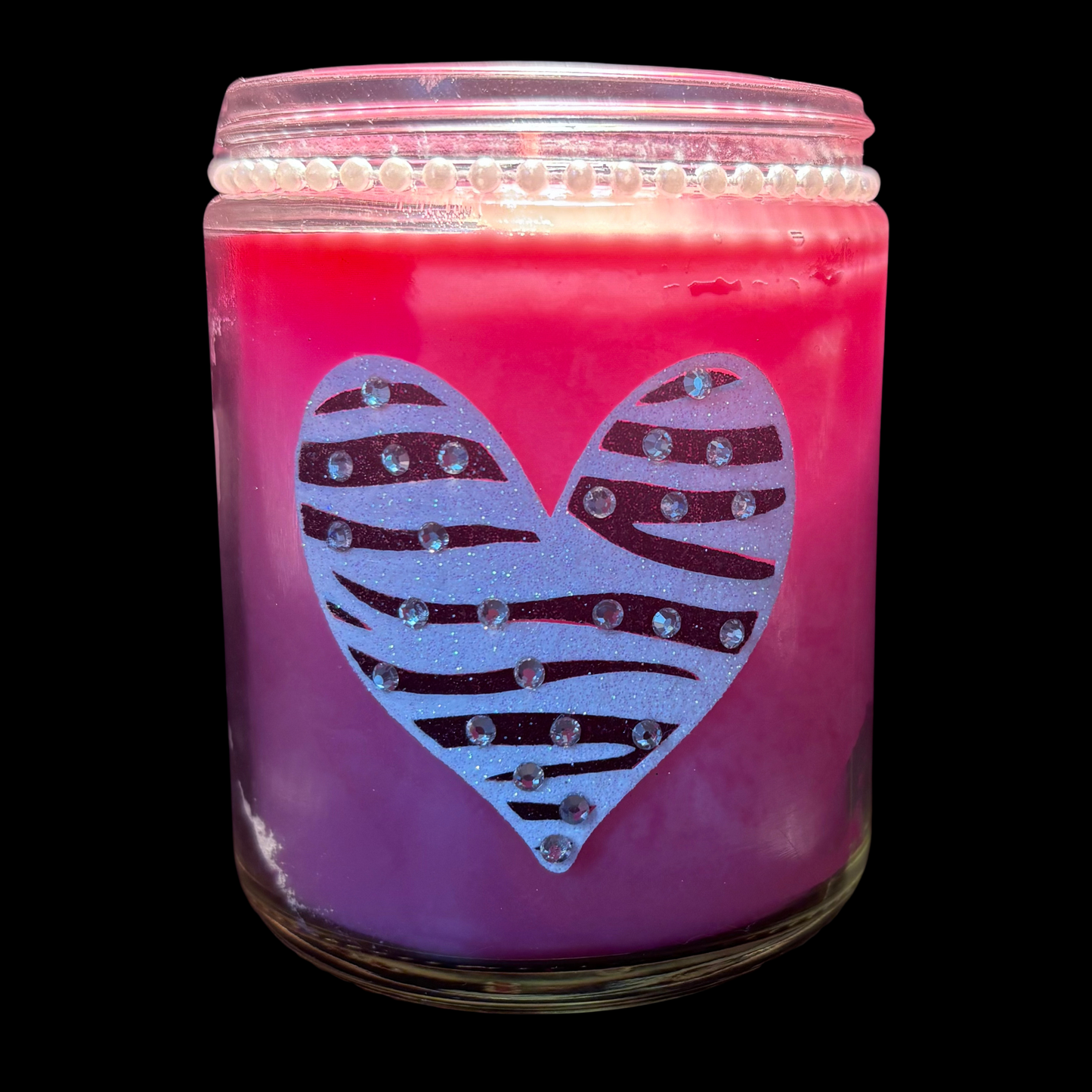 Pink candle jar with a zebra-striped heart design on a black background