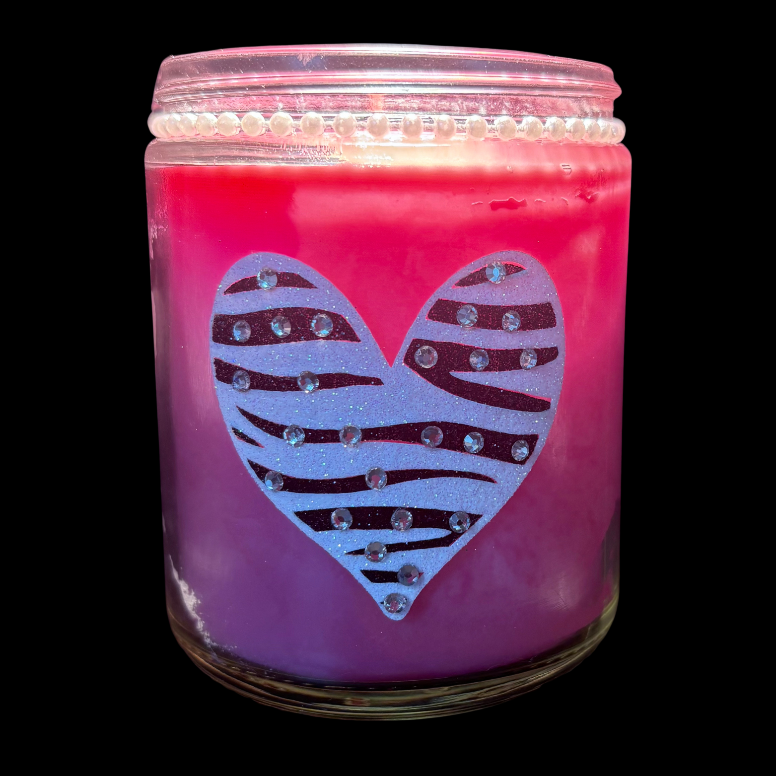 Pink candle jar with a zebra-striped heart design on a black background