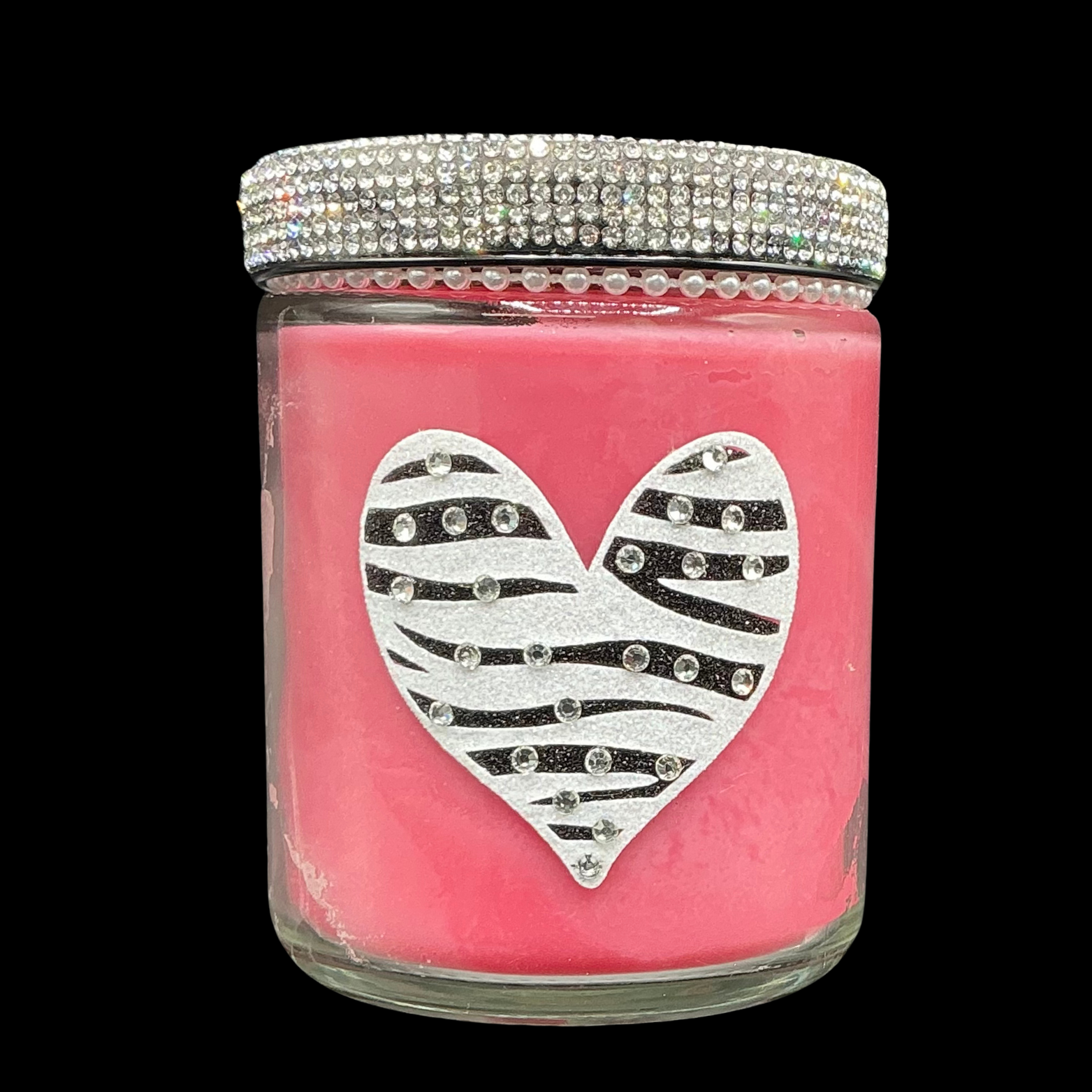 Pink candle jar with a silver zebra-striped heart design and rhinestone lid on a black background