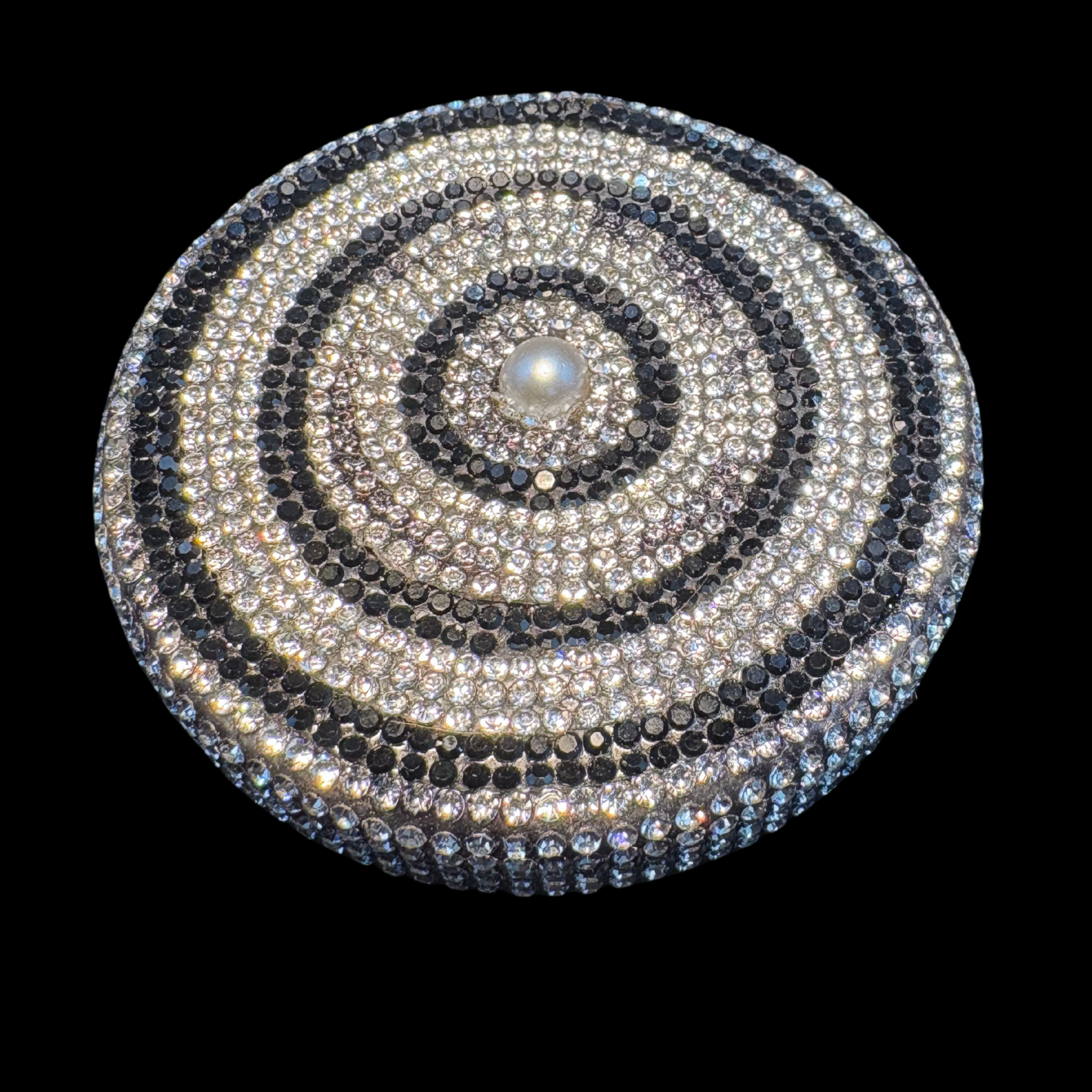Circular decorative item with concentric black and silver rings on a black background