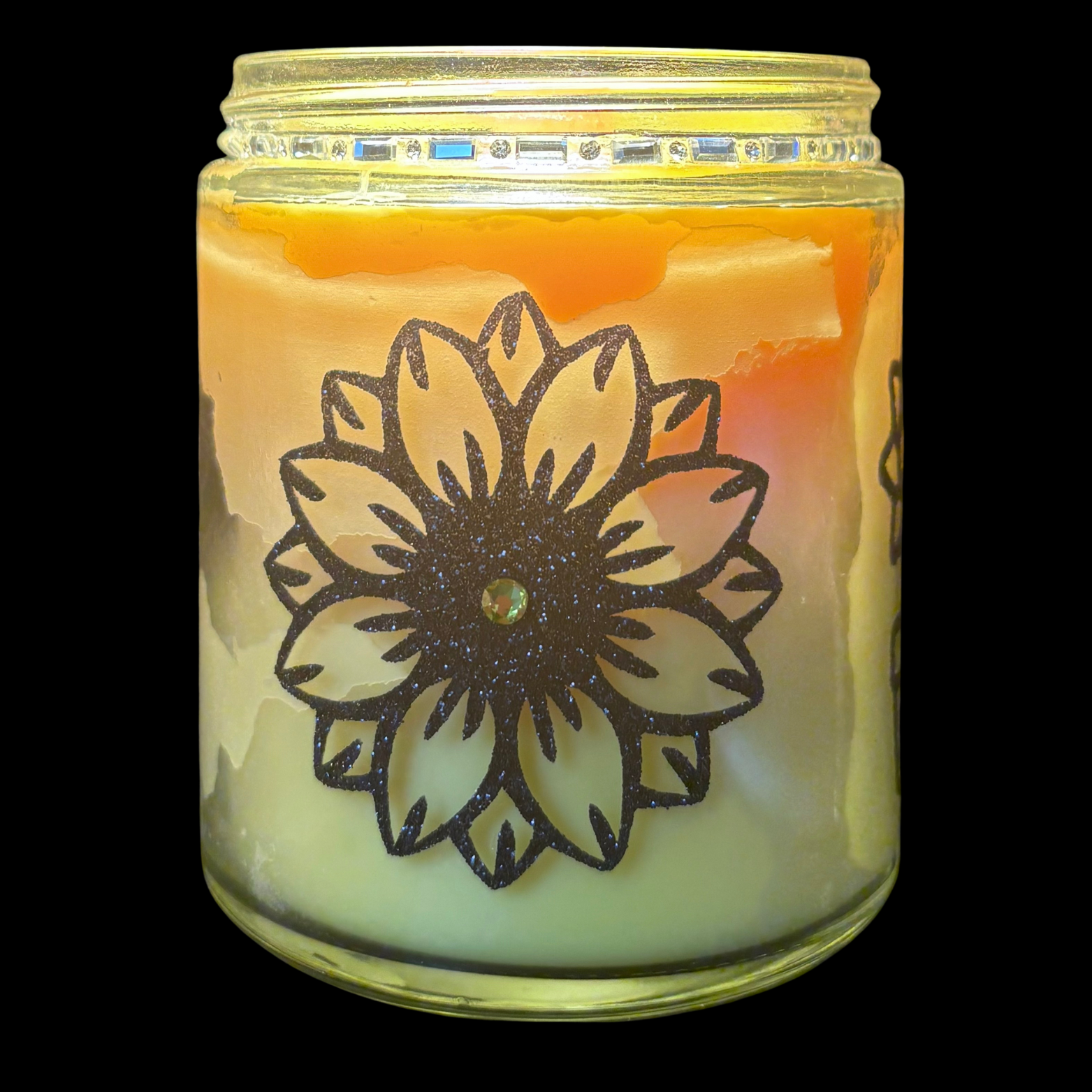 Candle in a glass jar with a floral design on a black background