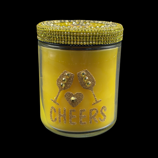 Yellow candle jar with 'Cheers' text and wine glass design on a black background