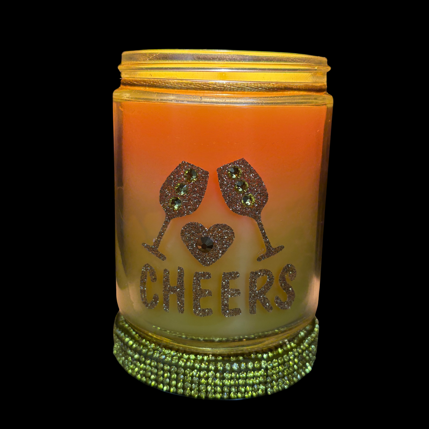 Decorative candle with 'Cheers' text and wine glass design on a golden background